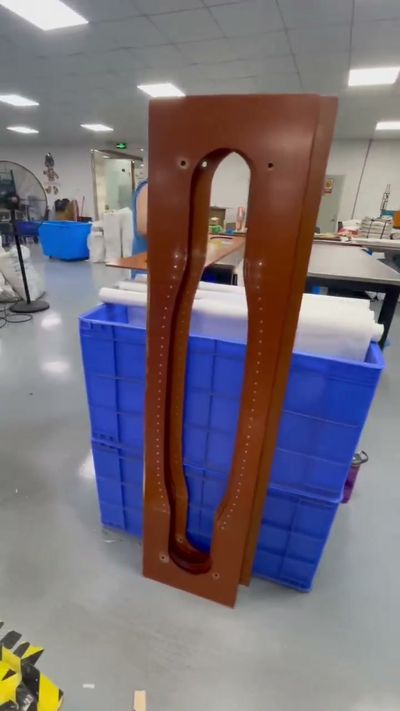 Brown formed component beside blue production bins in a workshop.